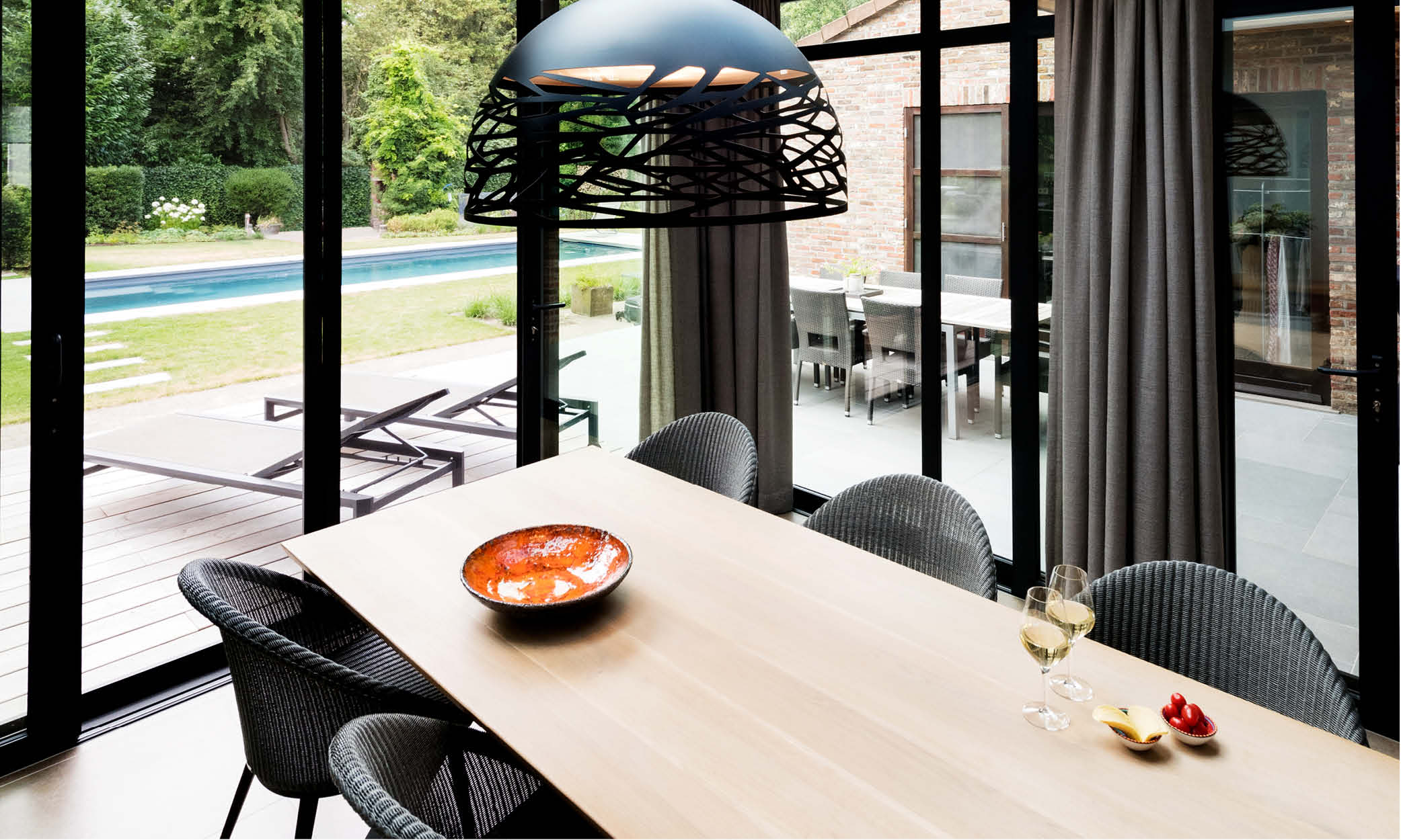 Moderne leefveranda met houten tafel met wijnglazen